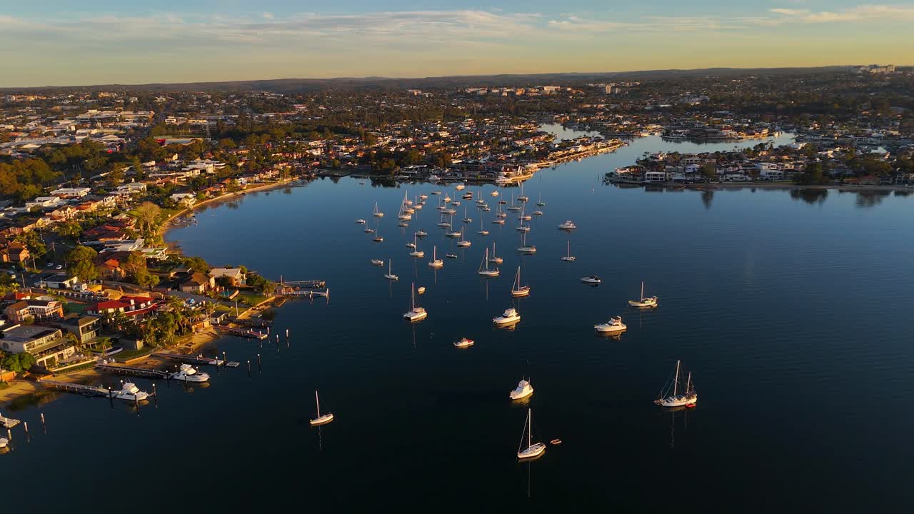 Aerial of luxury homes on canals in Sylvania Waters with sailboats and yachts anchored in tranquil setting, Sydney NSW Australia
