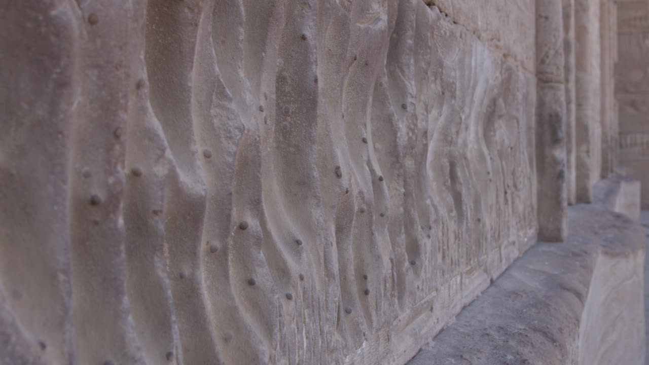 Ancient stone carvings, intricate patterns and textures on a weathered wall in Dendera