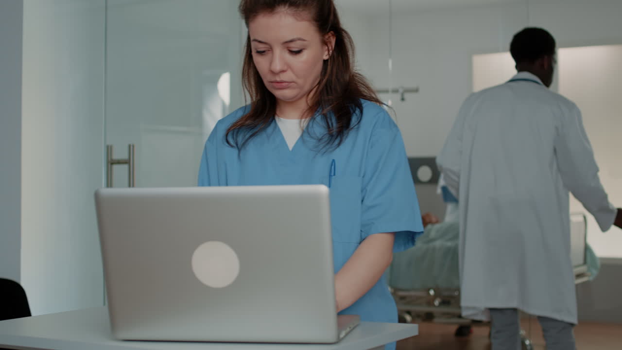 Medical assistant working with computer to help doctor