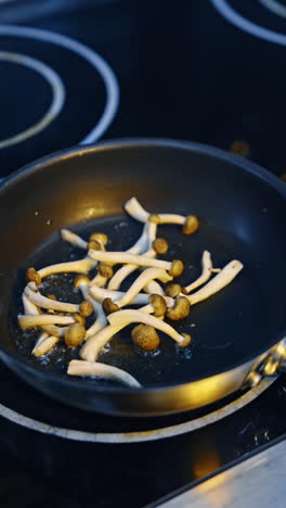 frying pan on the stove with hot vegetable or olive oil in. unrecognized cook's hand puts a pile of mushrooms to fry and moves the pan. close up. vertical video.