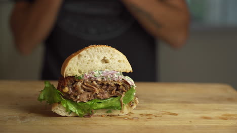 Man-taking-a-half-of-a-burger-from-a-wooden-board-and-eating-it