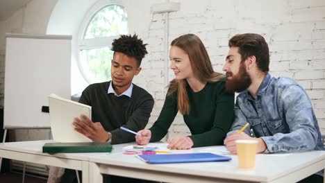 young african guy showing the results of his work to his colleagues. happy diverse group of students or young business team
