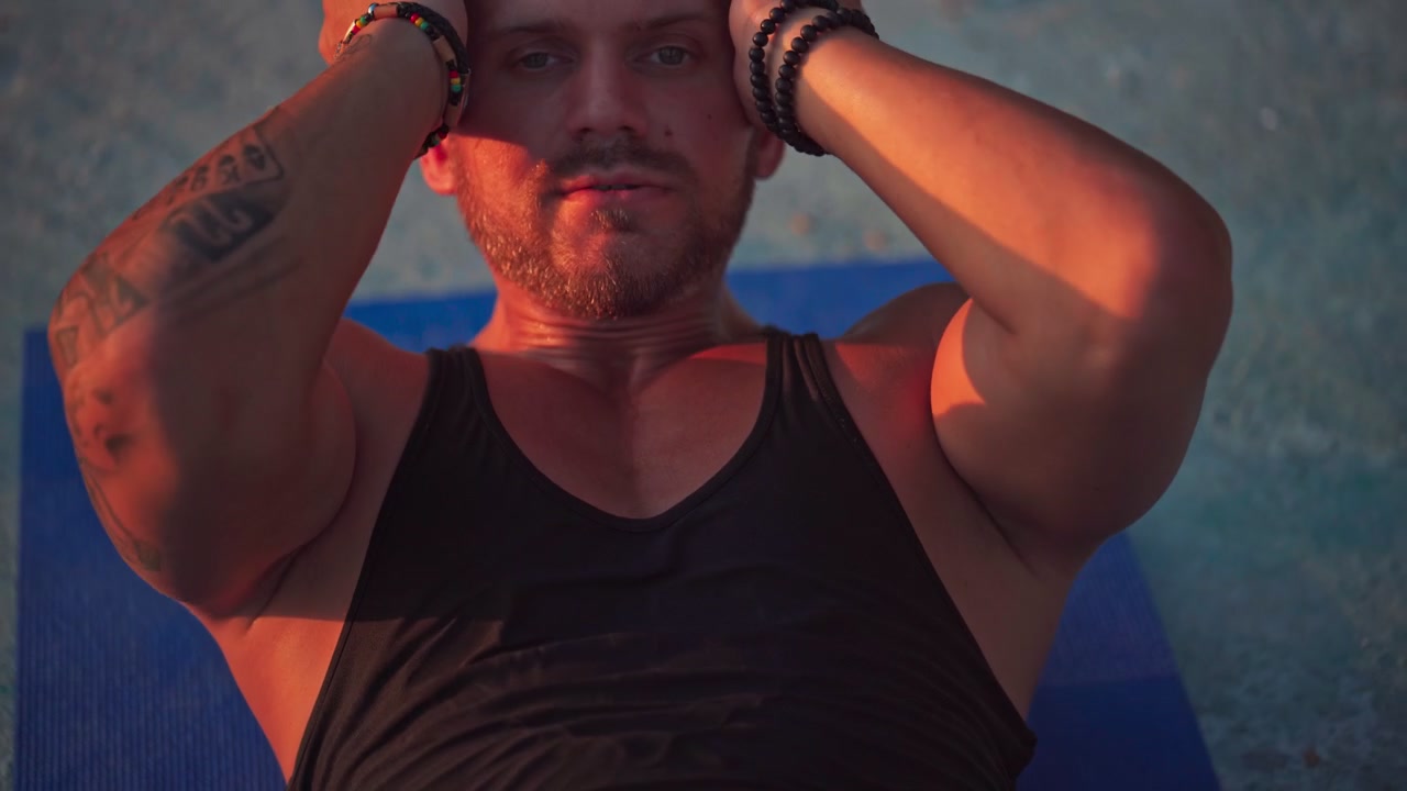 Uomo in forma che fa crunch su un tappetino da yoga al tramonto