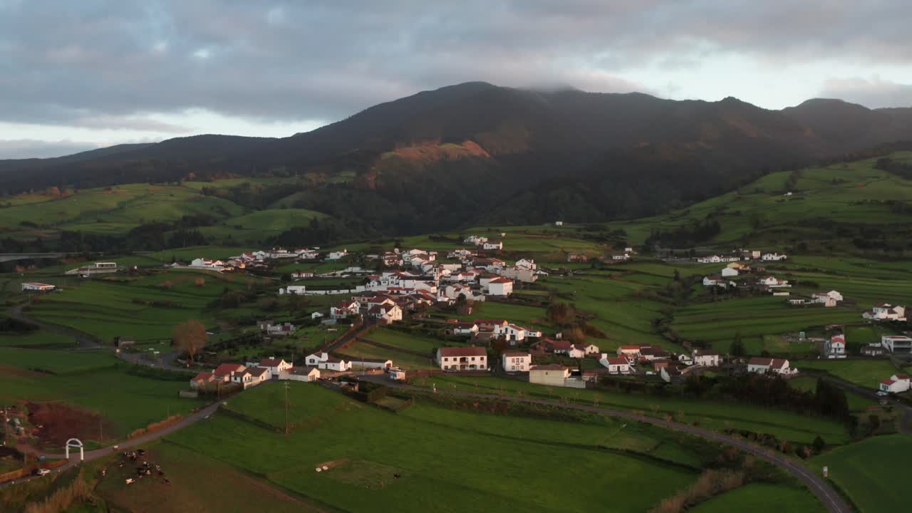 imágenes de drones del campo de la isla volcánica subtropical al atardecer con casas y carreteras con niebla y montaña cubierta de sol en el fondo