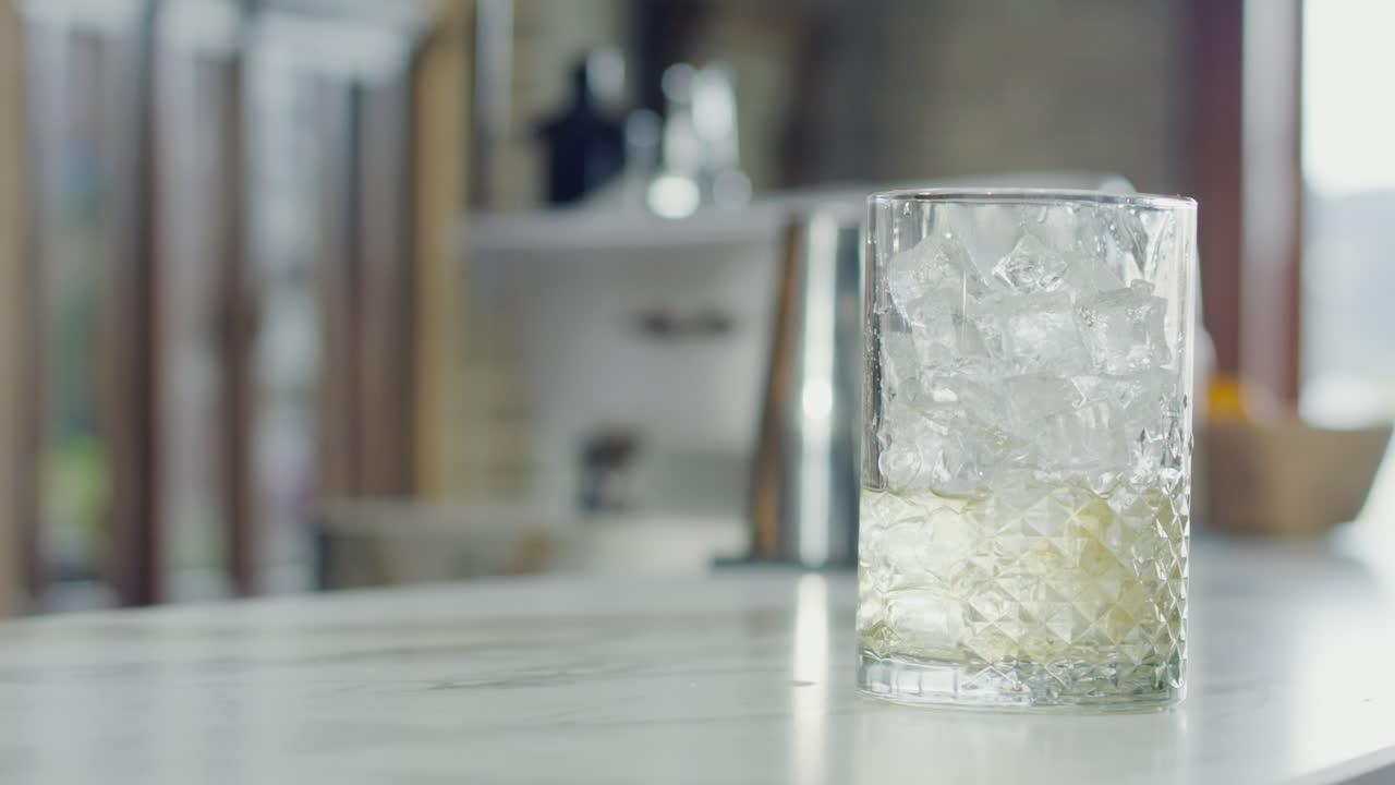 Close-up of a glass with ice and a ready cocktail, with a blurred bar background