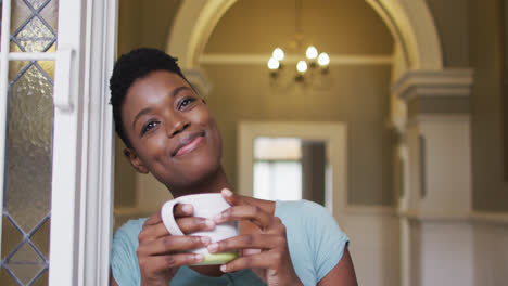 african american woman holding coffee cup smiling at home