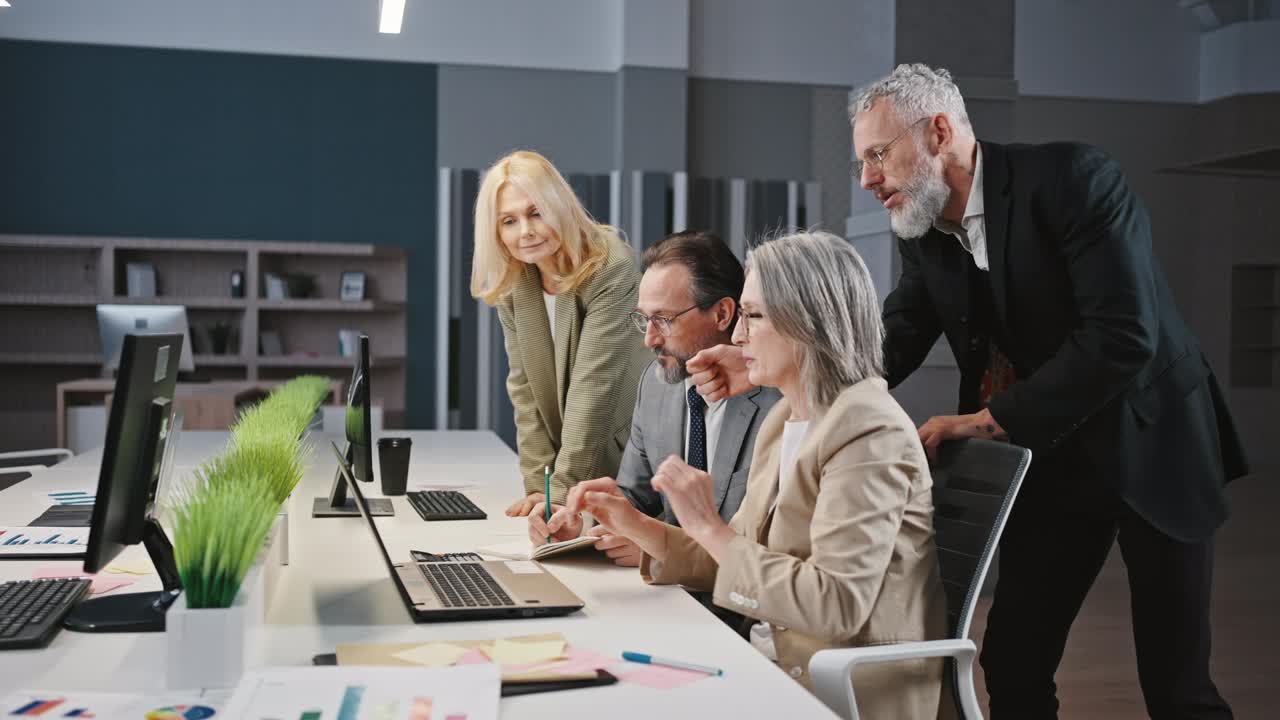 Group discussion. Mature colleagues discussing project, with laptop during meeting at office, tracking shot, slow motion
