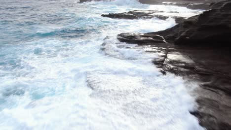 epic drone flight low above beautiful hawaii sea cliffs as big waves crash on top of the rocks