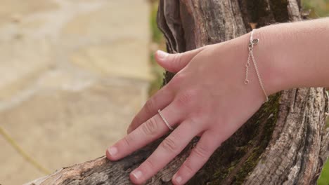 Hand-with-jewellery-slowly-caress-aged-vine-tree-wood-texture-close-up