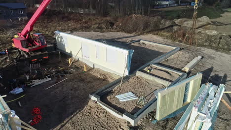 fotografía aérea de una grúa posicionando un panel de una casa en un sitio de construcción