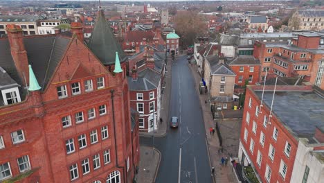 a red brick turreted building overlooks a quiet norwich street lined with shops