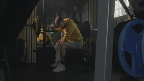 man resting after workout in home gym, using towel to wipe sweat