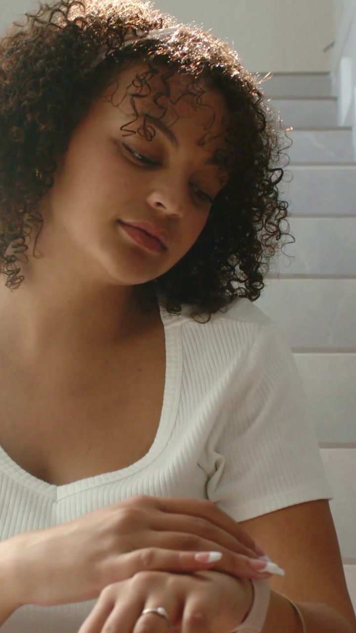 Vertical video: Fixing woman in white top brown pants touching light watch on stairs, checking time