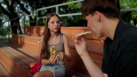 teenagers enjoying pizza together in a park