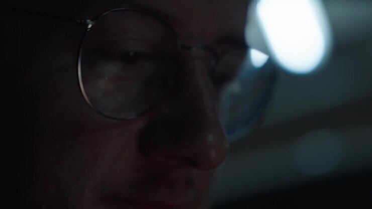Close up view of person wearing glasses in a dark environment.