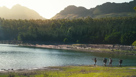 vista de gran ángulo de un grupo de amigos con mochilas en vacaciones de senderismo por el lago y las montañas