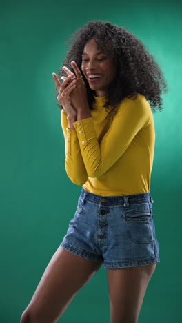 vertical video: joyful woman in yellow top and denim shorts clapping hands, feeling excited