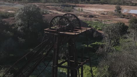 Drone-shot-of-an-old-rusty-elevator-shaft-in-the-ghost-town-of-Sao-Domingo-Mines,-Portugal