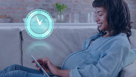 animation of clock over biracial pregnant woman using tablet