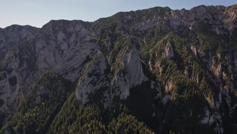 Majestic-Piatra-Craiului-Mountains-with-dense-forests-and-rugged-cliffs-at-sunset,-aerial-view