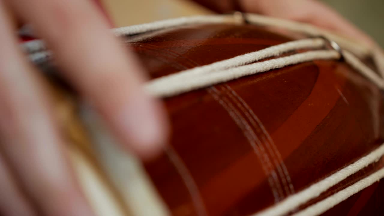 Close up of hands of a man playing a drum.
