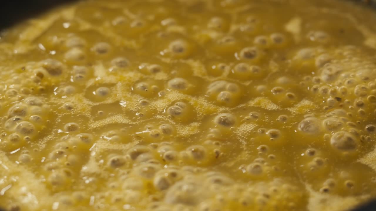 Green boiling sauce texture close-up macro. Cooking green curry with wooden spoon at home.