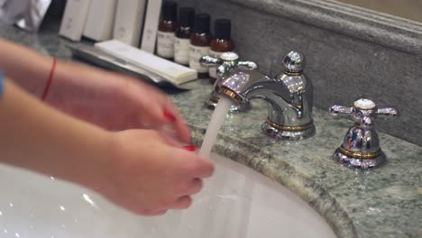 Woman-turning-bathroom-faucet-and-washing-hands-in-in-bathroom-sink