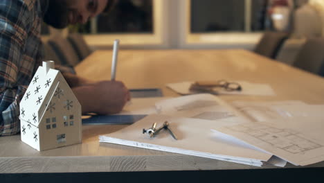 arquitecto usando lápiz y papel para crear planos en un escritorio de madera