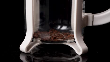 Close-up-shot-of-making-fresh-coffee-with-French-Press-coffee-machine-with-black-background