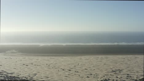 descending aerial of oregon coast dunes and far away forest