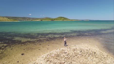 A-woman-dancing-on-the-beach-of-the-island-of-Galesnjak-in-Dalmatia,-Croatia