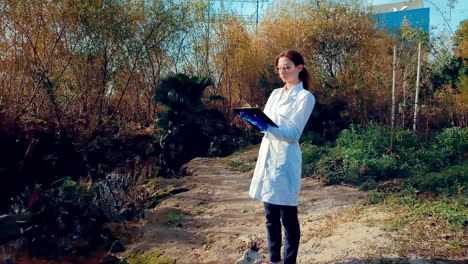 a young woman scientist at a creek, wearing protective eyewear and a lab coat