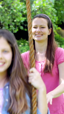 mother pushing her daughter on a swing