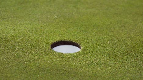 a golf ball missing the hole, then being hit in the hole