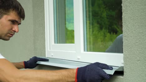 man worker in protective gloves measuring external frame and pvc window metal sill size