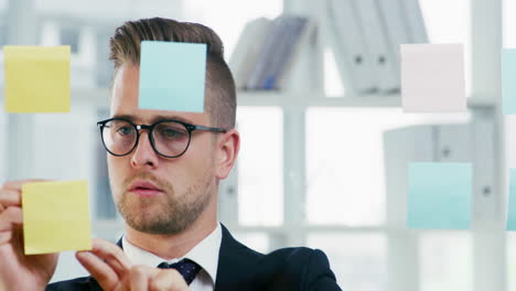 a young businessman writing notes on a glass wall