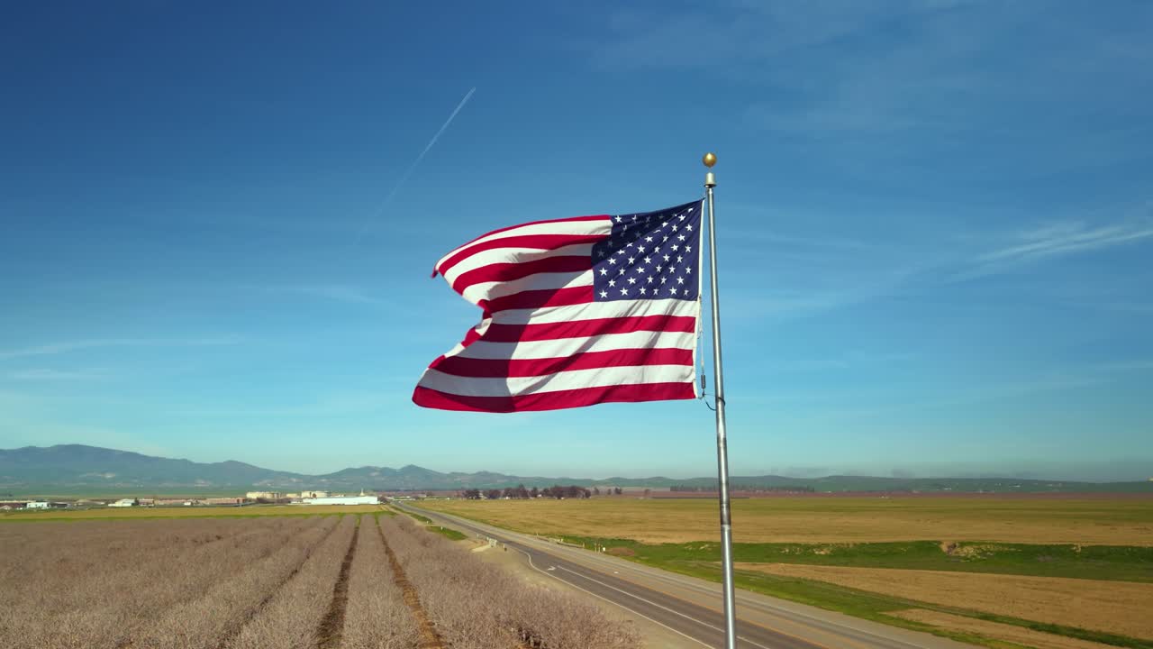 Bandiera americana che sventola nel vento, simbolo patriottico con cielo blu e montagne sullo sfondo
