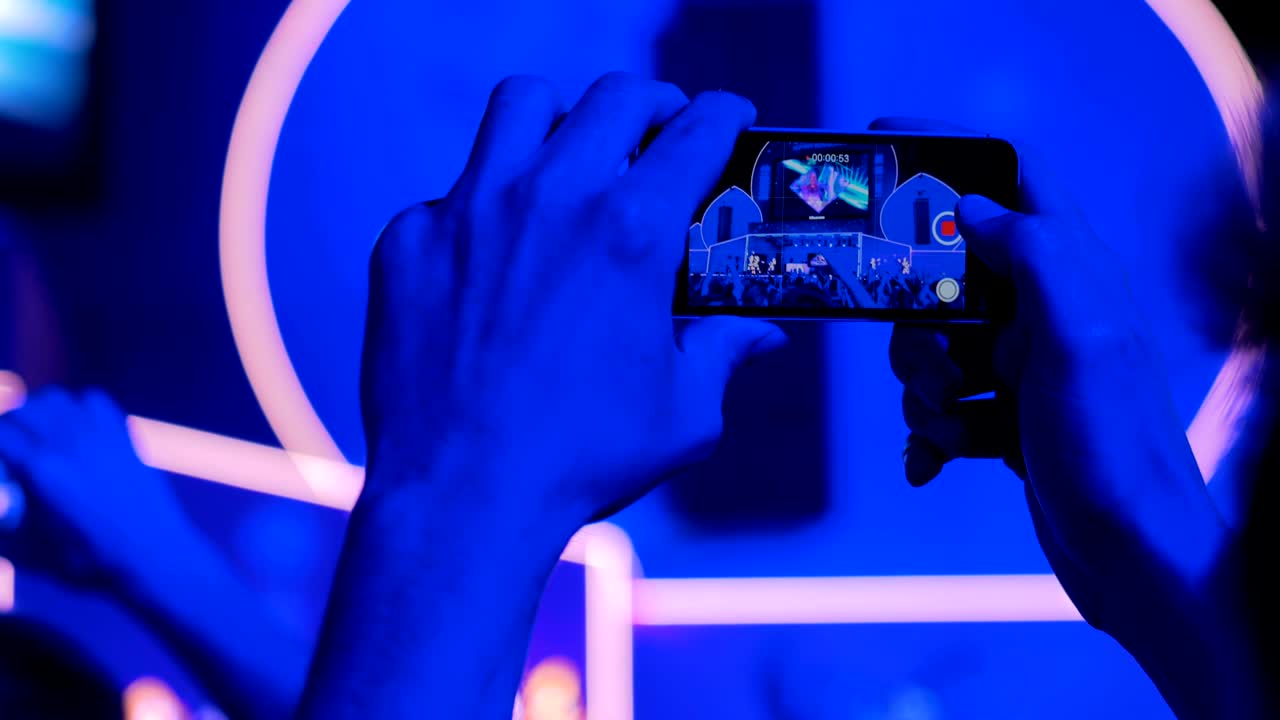 Hands silhouette recording video of live music concert with smartphone