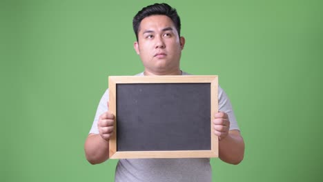 young handsome overweight asian man against green background