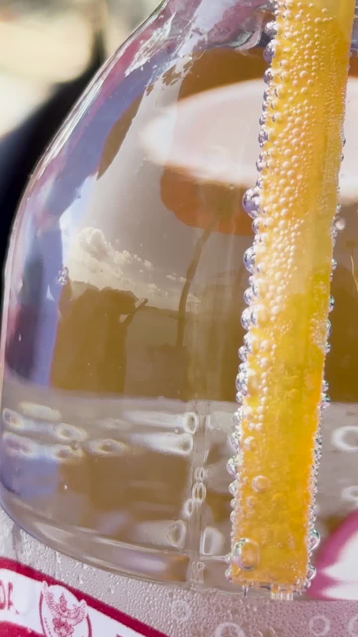 Close-up of bubbles forming around a straw in a soda bottle, showcasing cavitation phenomena in a bright setting