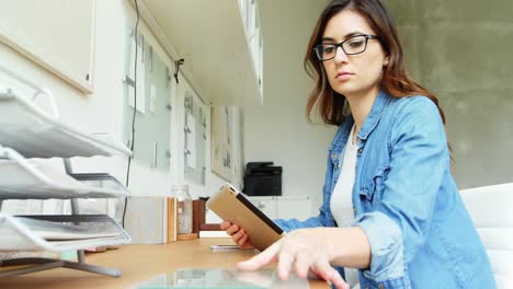 mujer ejecutiva mirando una hoja de vidrio mientras usa una tableta digital