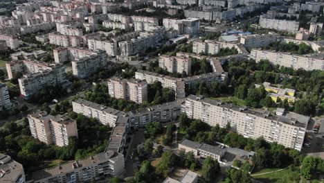 Aerial-View-of-Geometrically-Shaped-Buildings-in-a-City-Surrounded-by-Trees-Slowly-Descending