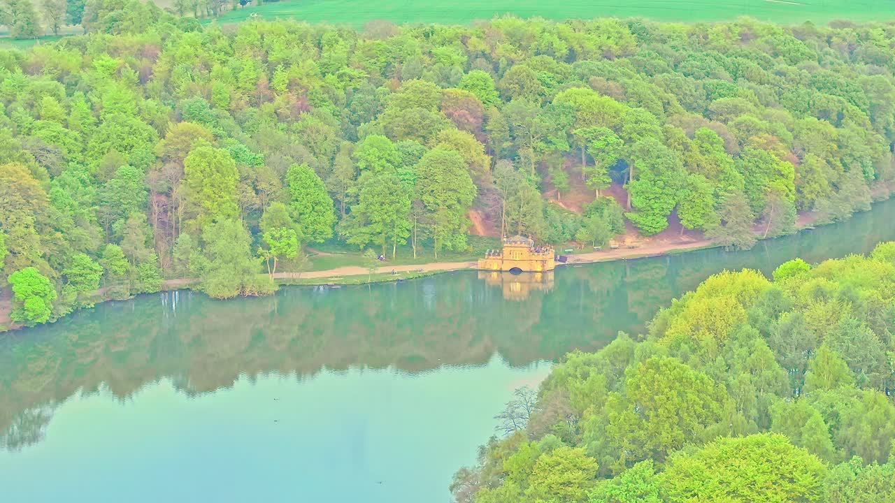 Aerial: house on the lake in Newmillerdam Country Park during the day in Newmillerdam, suburb of Wakefield, West Yorkshire, England, crane down drone shot