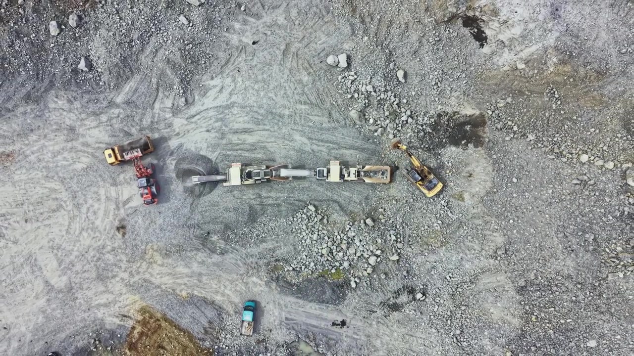 Granite quarry operation with various machines and trucks working in a mining site in a rural area during daylight hours