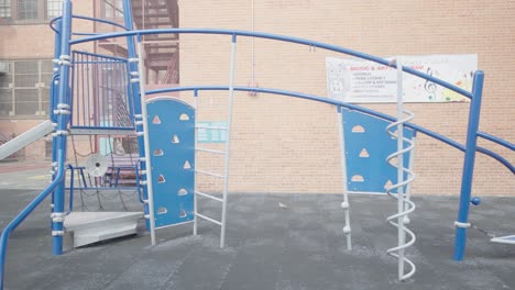 a vibrant blue and white jungle gym stands ready for play outside a bustling new york city school, full of potential adventures