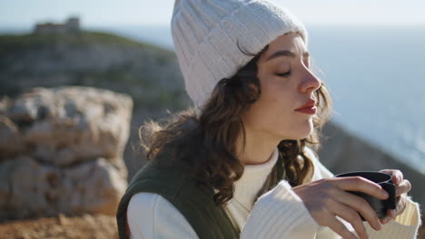 Adventure-woman-drink-coffee-ocean-picnic-vertical-closeup.-Serene-morning-time