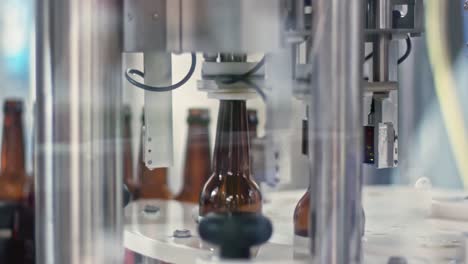 en la cervecería, la máquina coloca las botellas debajo de la boquilla para llenarlas con cerveza.