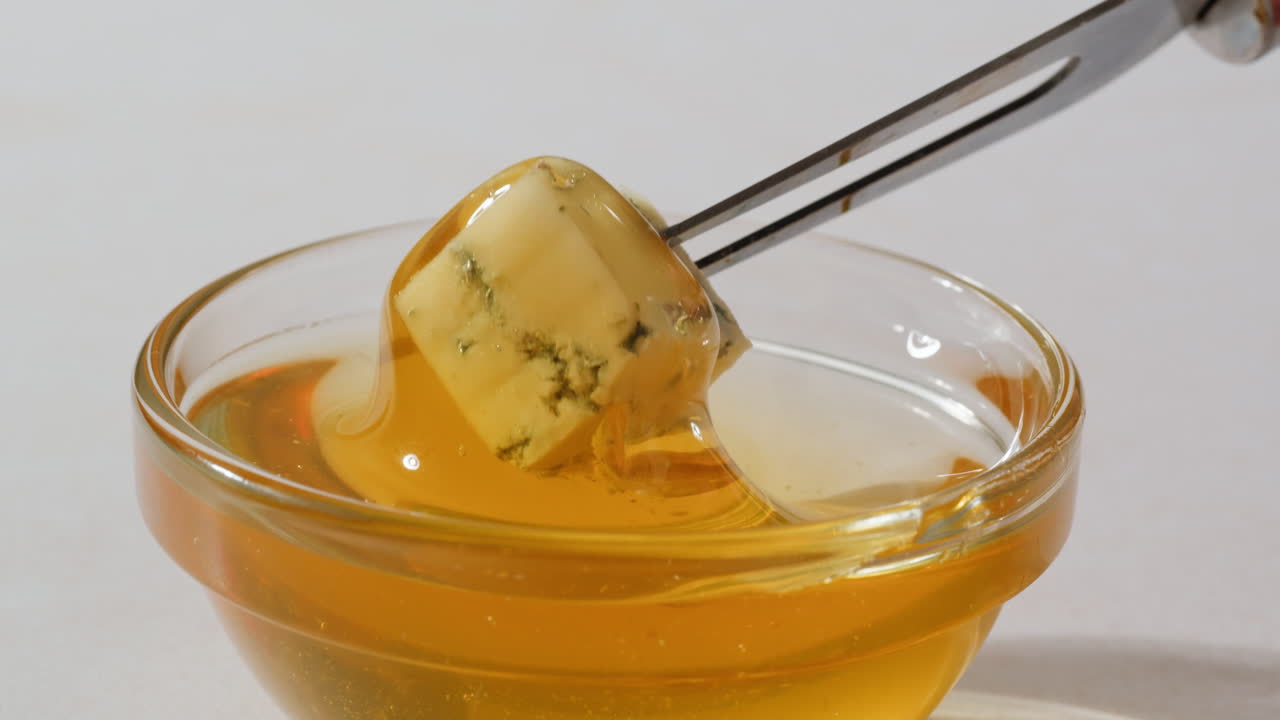 Tasty blue cheese with rosemary, honey and walnuts on white table, close up of Dorblu in cafe pouring in honey.