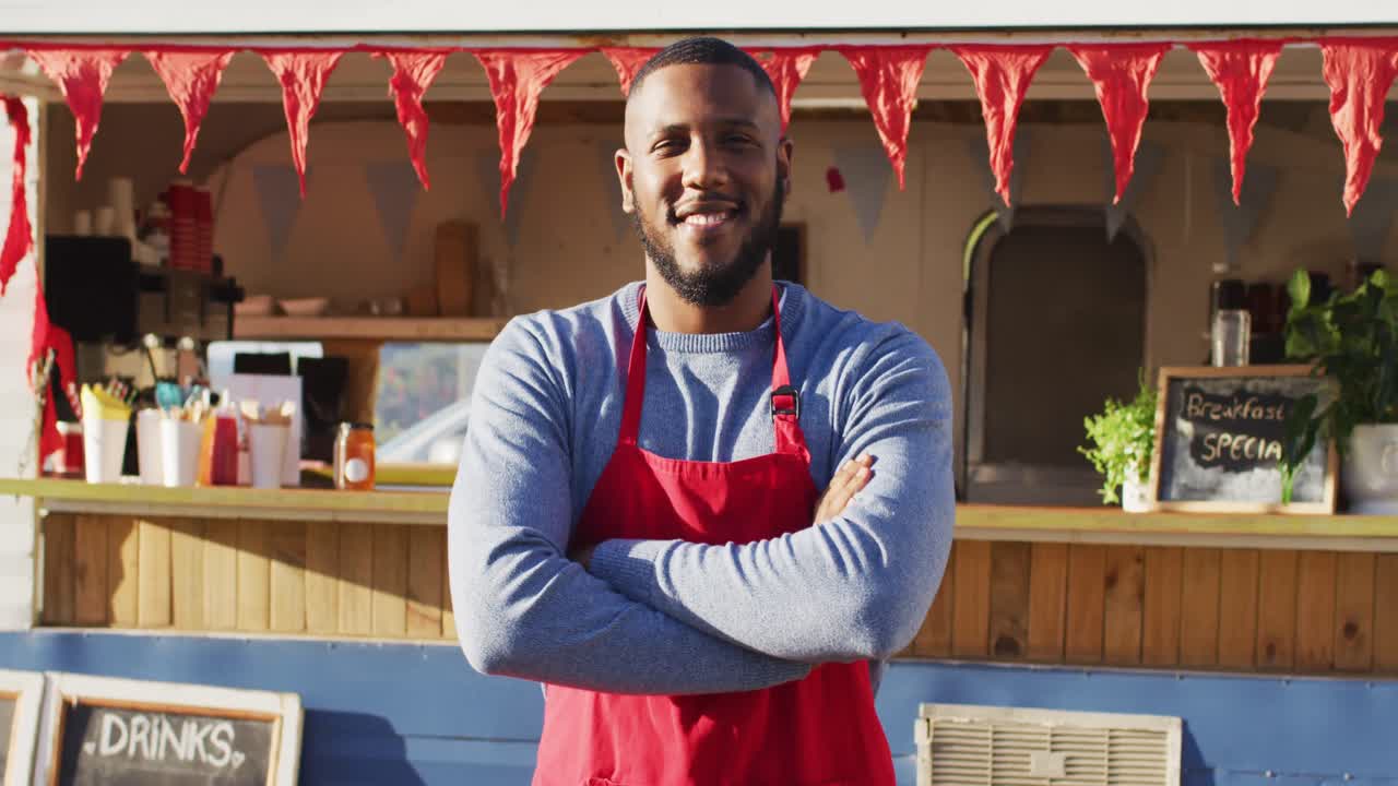 retrato de un hombre afroamericano con los brazos cruzados sonriendo mientras estaba de pie cerca del camión de comida