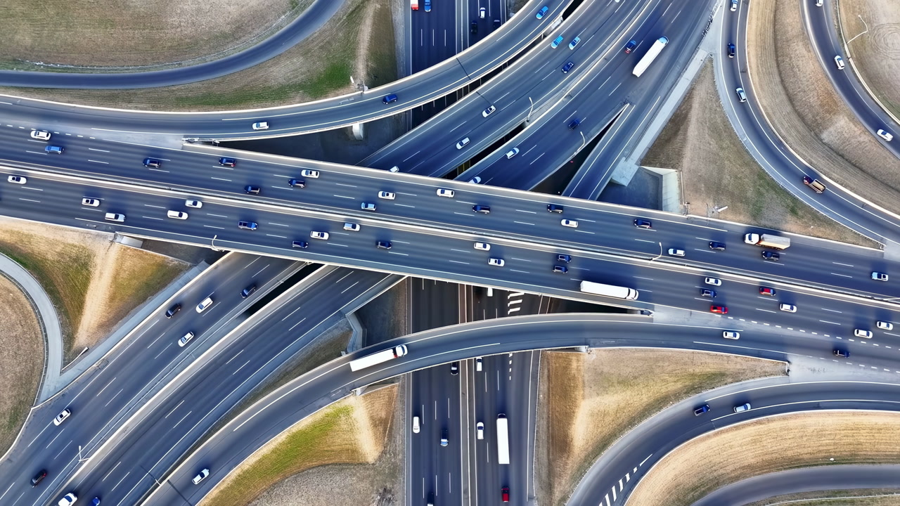 Aerial Highway Interchange Busy Traffic Ramps, Layered Overpasses And Sweeping Curves, Trucks And Cars Moving